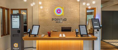 A reception desk with a logo, a digital kiosk, and a self-service machine.