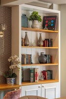 A bookshelf with books, vases, and a plant.