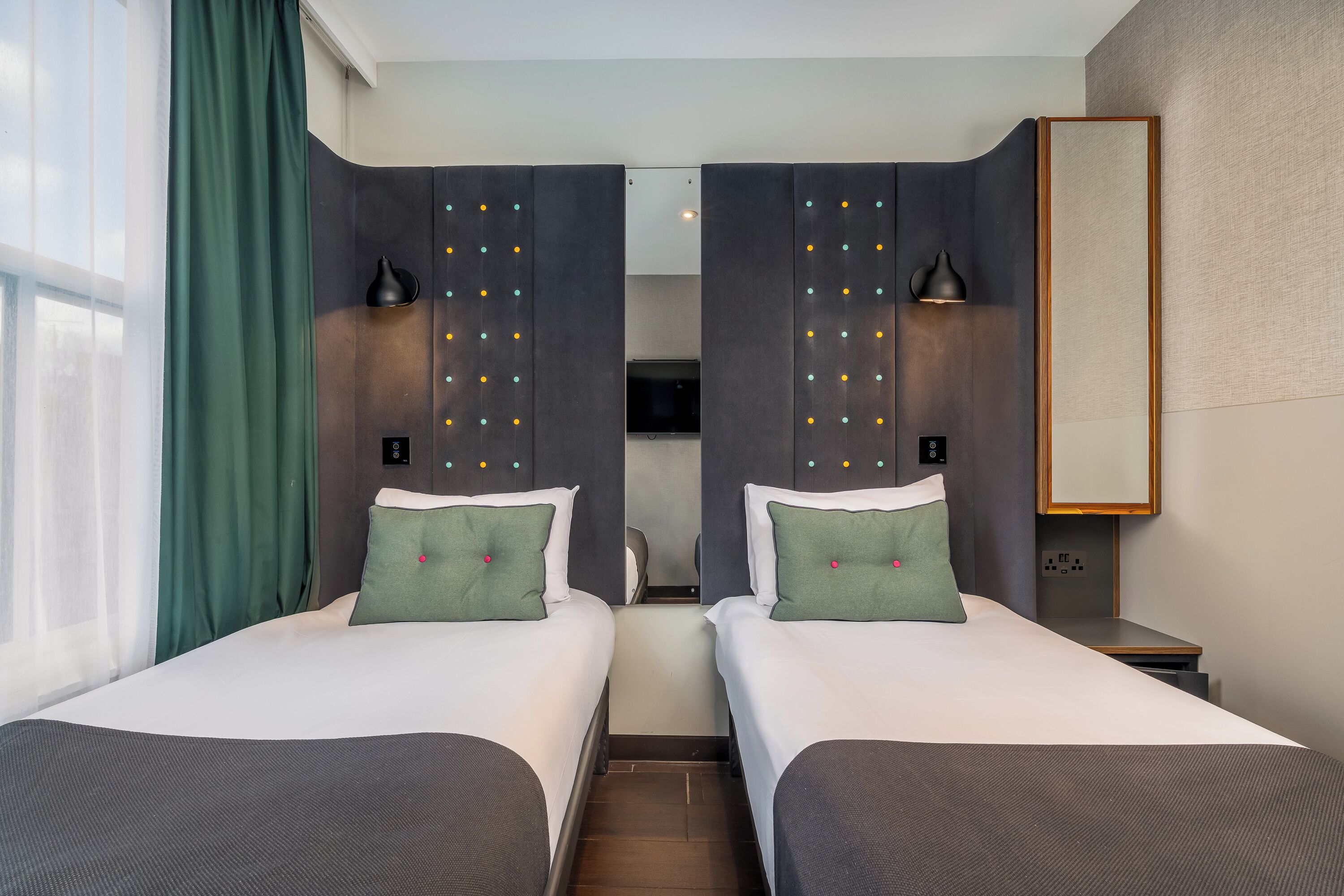 Ein Hotelzimmer mit zwei Betten, einem großen Spiegel und einem Fernseher.