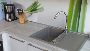 Uma cozinha moderna com pia de aço inoxidável, cafeteira e porta-facas.