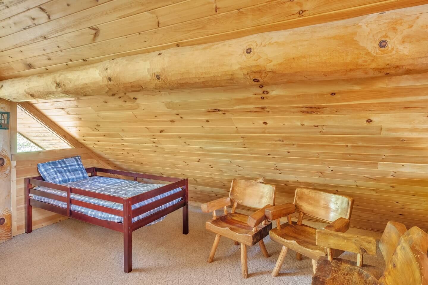 Interior de cabana de madeira com beliche, duas cadeiras de madeira e piso coberto de carpete.