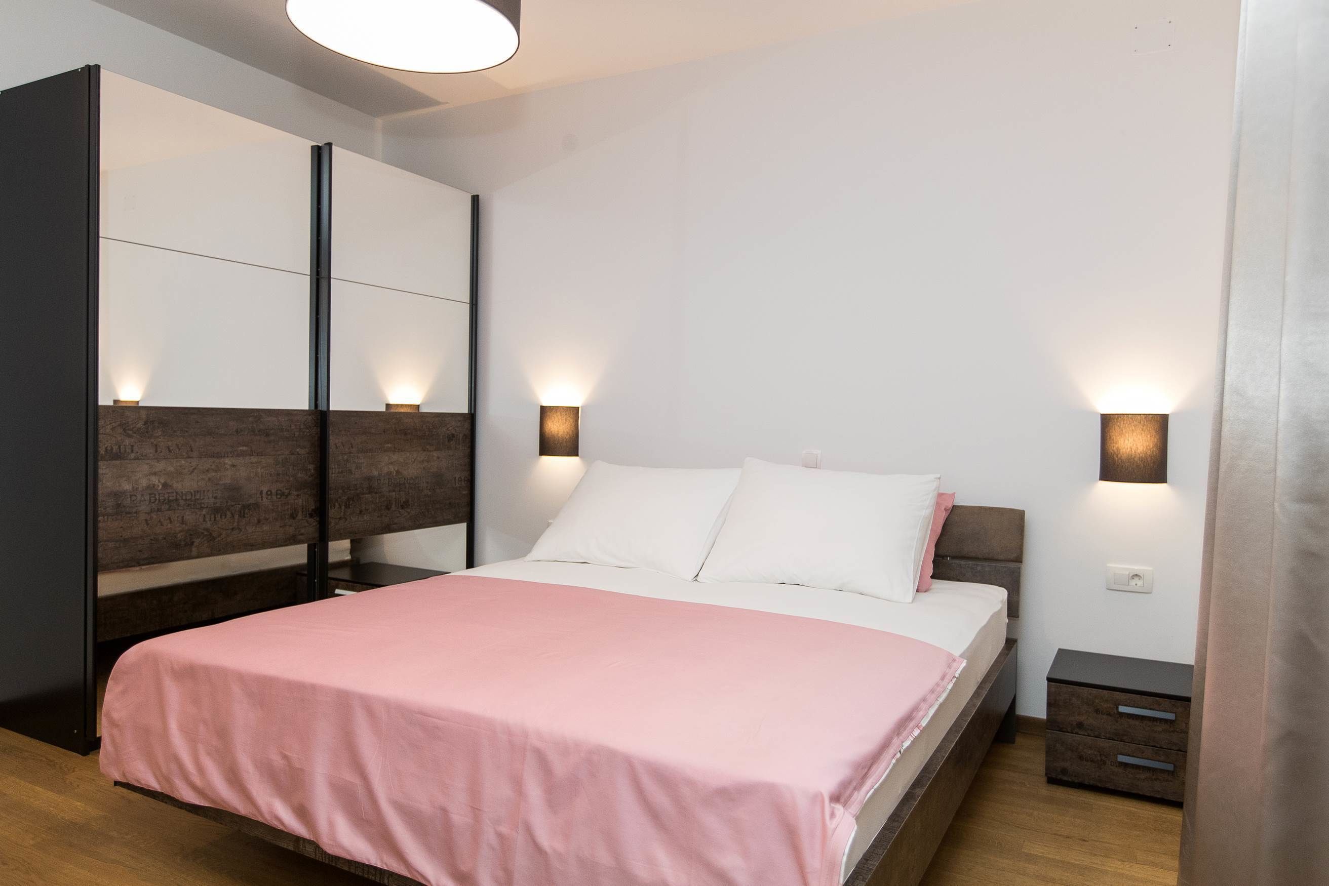 Un dormitorio moderno con cama, mesitas de noche e iluminación en la pared.