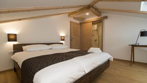 A bedroom with a large bed, wooden beams, a desk, and a wardrobe. - Pansion Preza (Crikvenica)
