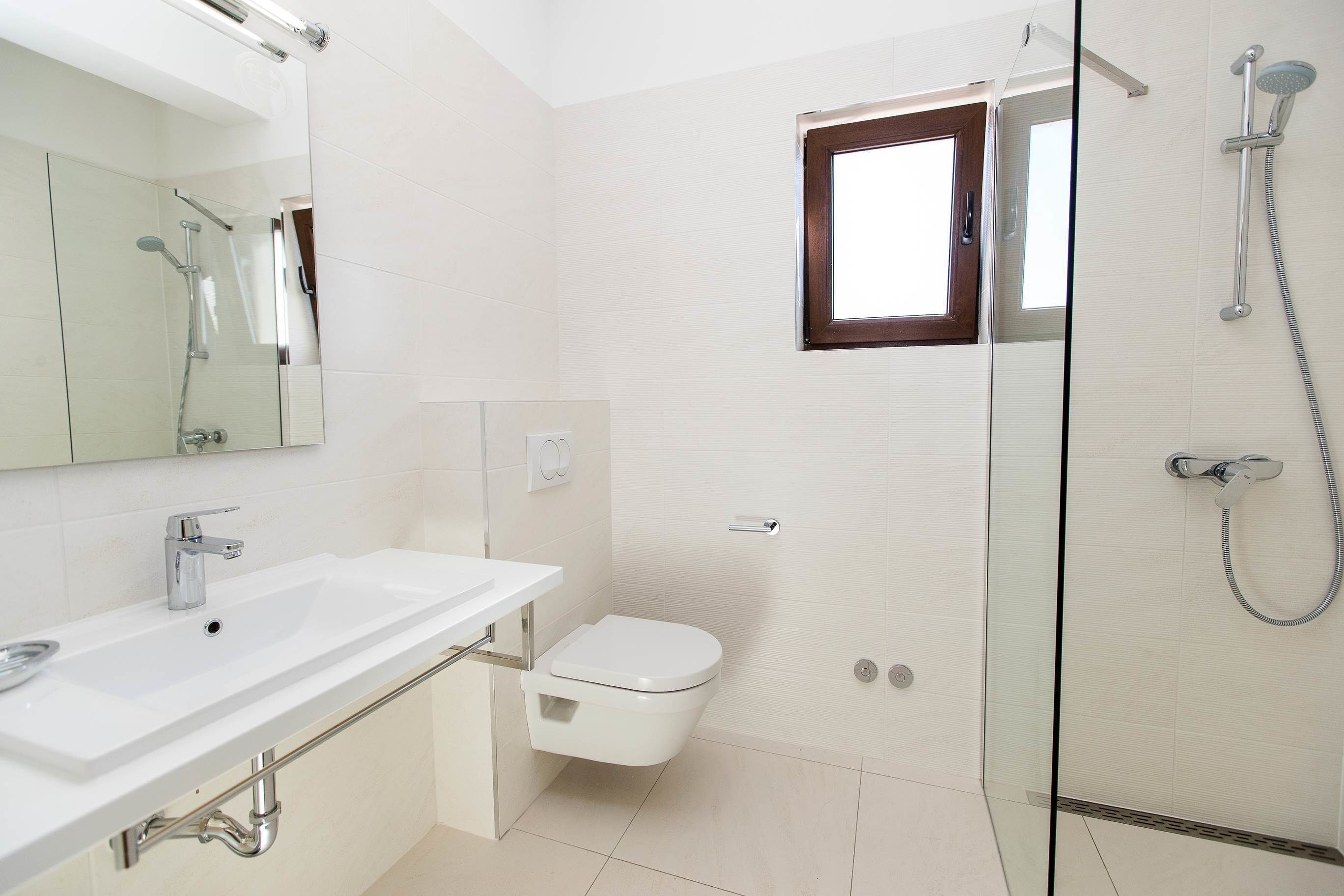 Un baño moderno con cabina de ducha de vidrio, un lavamanos blanco y un inodoro.