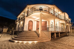 A two-story building with a curved balcony, a staircase leading to the entrance, and a paved driveway. - Pansion Preza (Crikvenica)