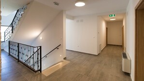 A spacious hallway with a staircase on the left, a door on the right, and a vent on the wall. - Pansion Preza (Crikvenica)