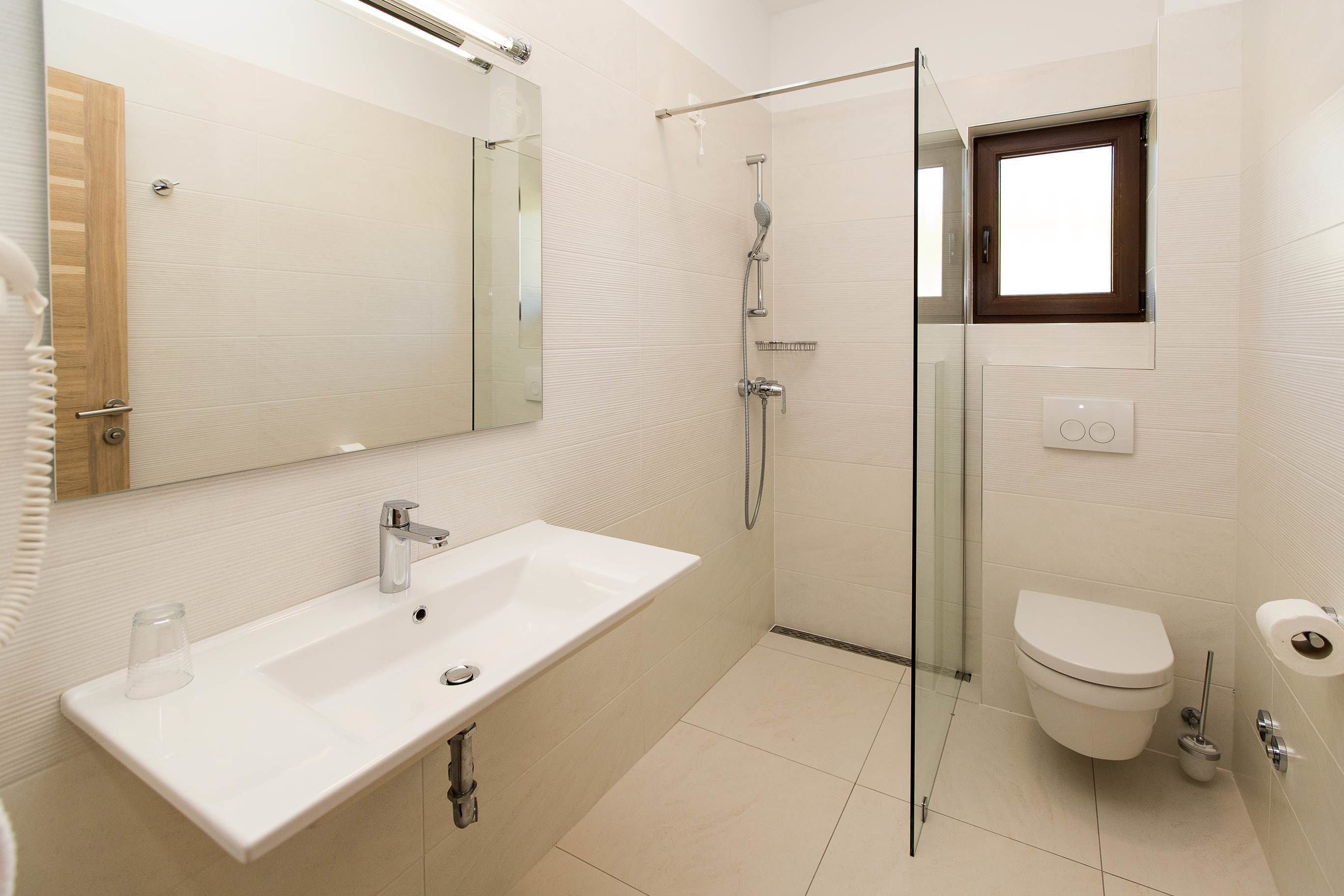 Une salle de bain moderne avec une douche à parois de verre, un lavabo blanc et des toilettes.