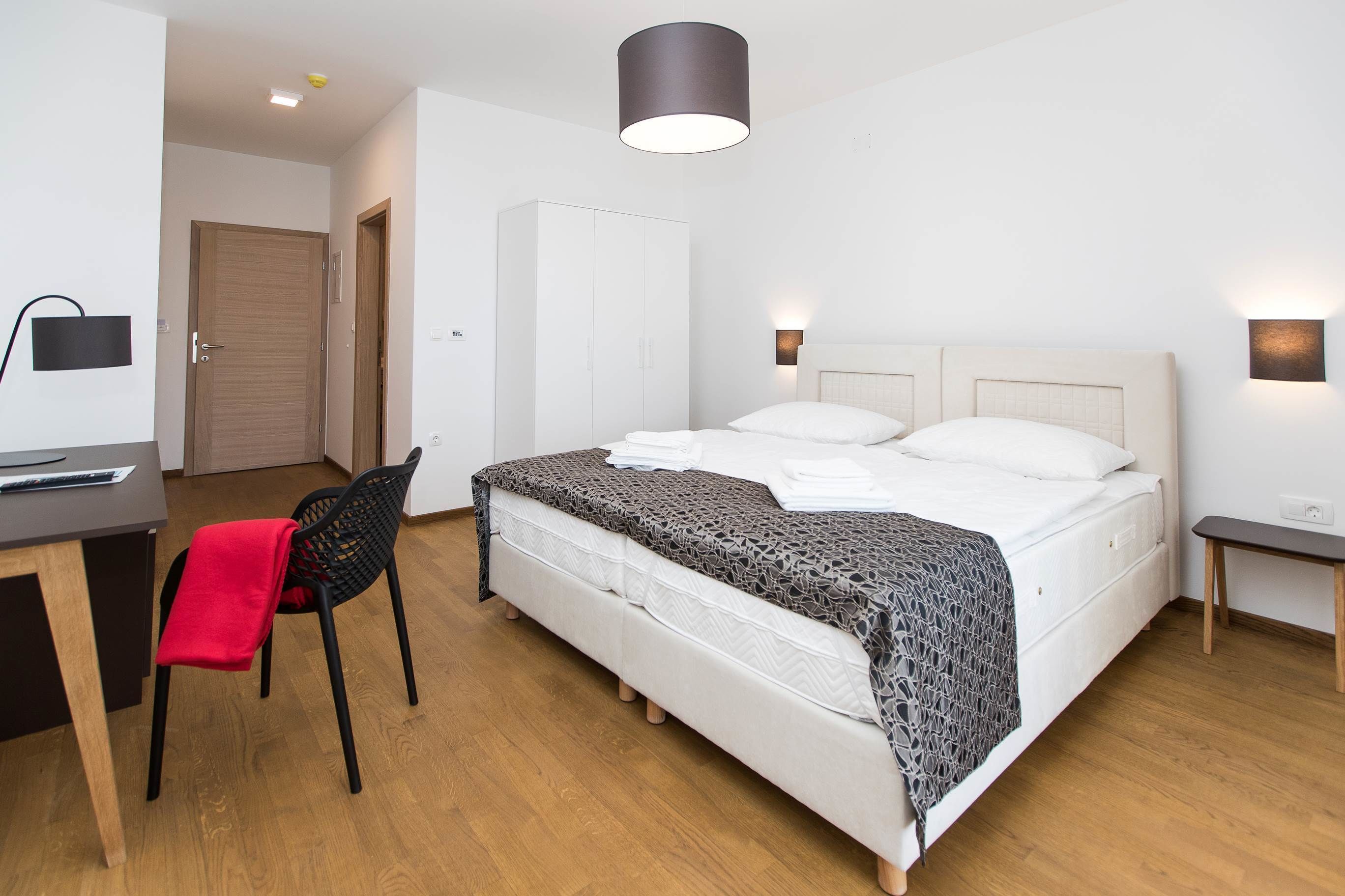 Een moderne slaapkamer met een bed, nachtkastjes, een bureau en een stoel.