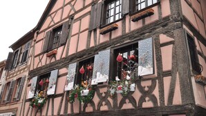 Ein Fachwerkhäuschen mit zahlreichen Fenstern, verziert mit festlichen Girlanden und Schmuck.