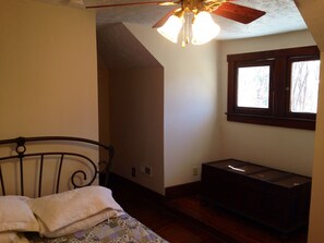 A bedroom with a bed, a dresser, a ceiling fan, and a window.