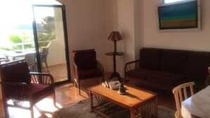 Uma sala de estar com sofá, poltronas, mesa de centro e luminária.