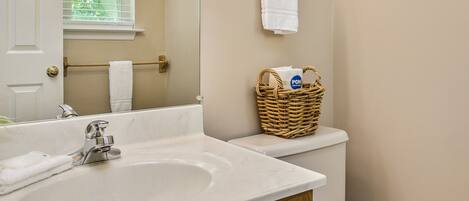 Een badkamer met een witte wastafel, een houten opbergmeubel en een houten toilet.