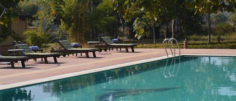 A pool area with lounge chairs and a clear pool.