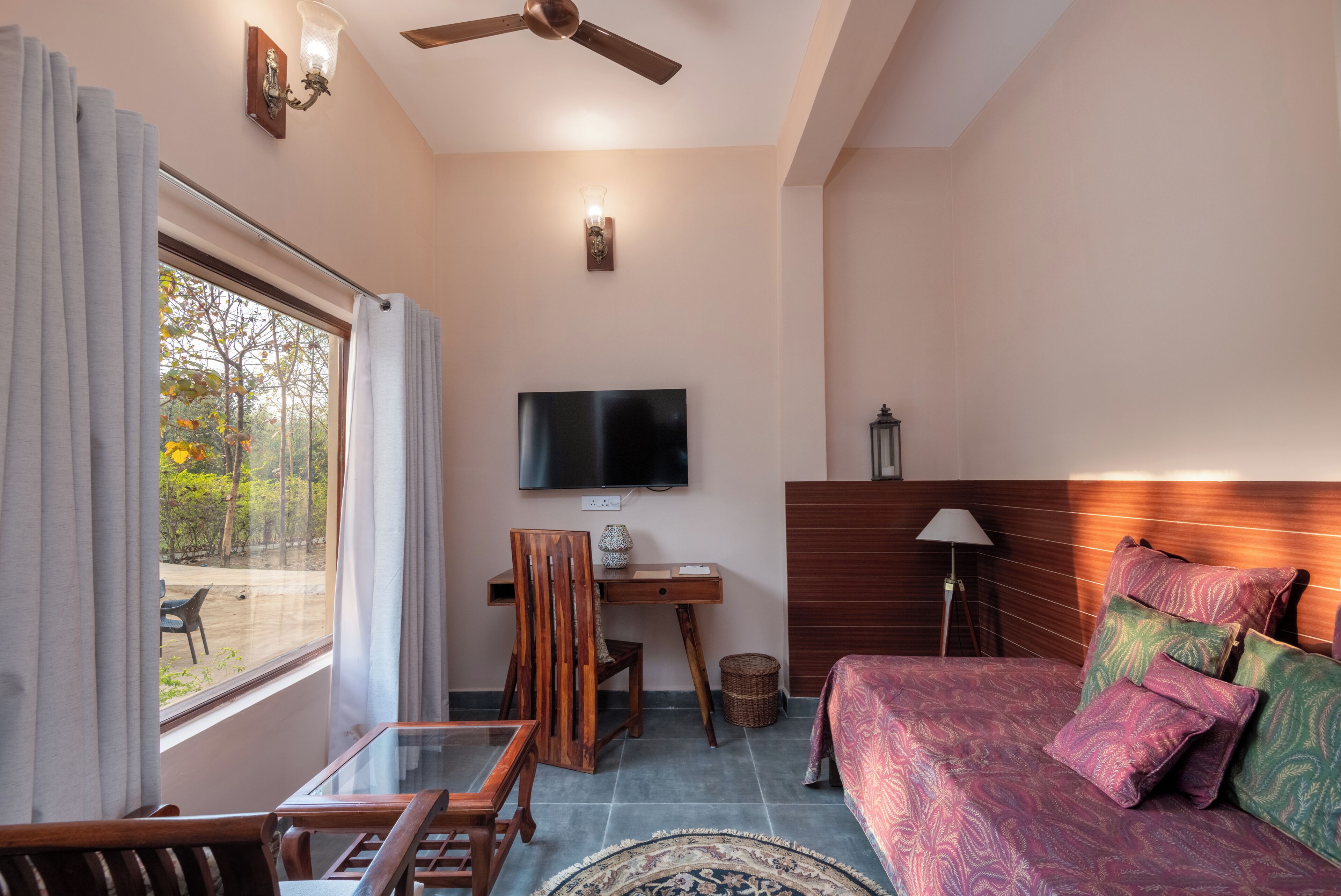 Una habitación con cama, escritorio, silla, televisor y ventana con cortinas.