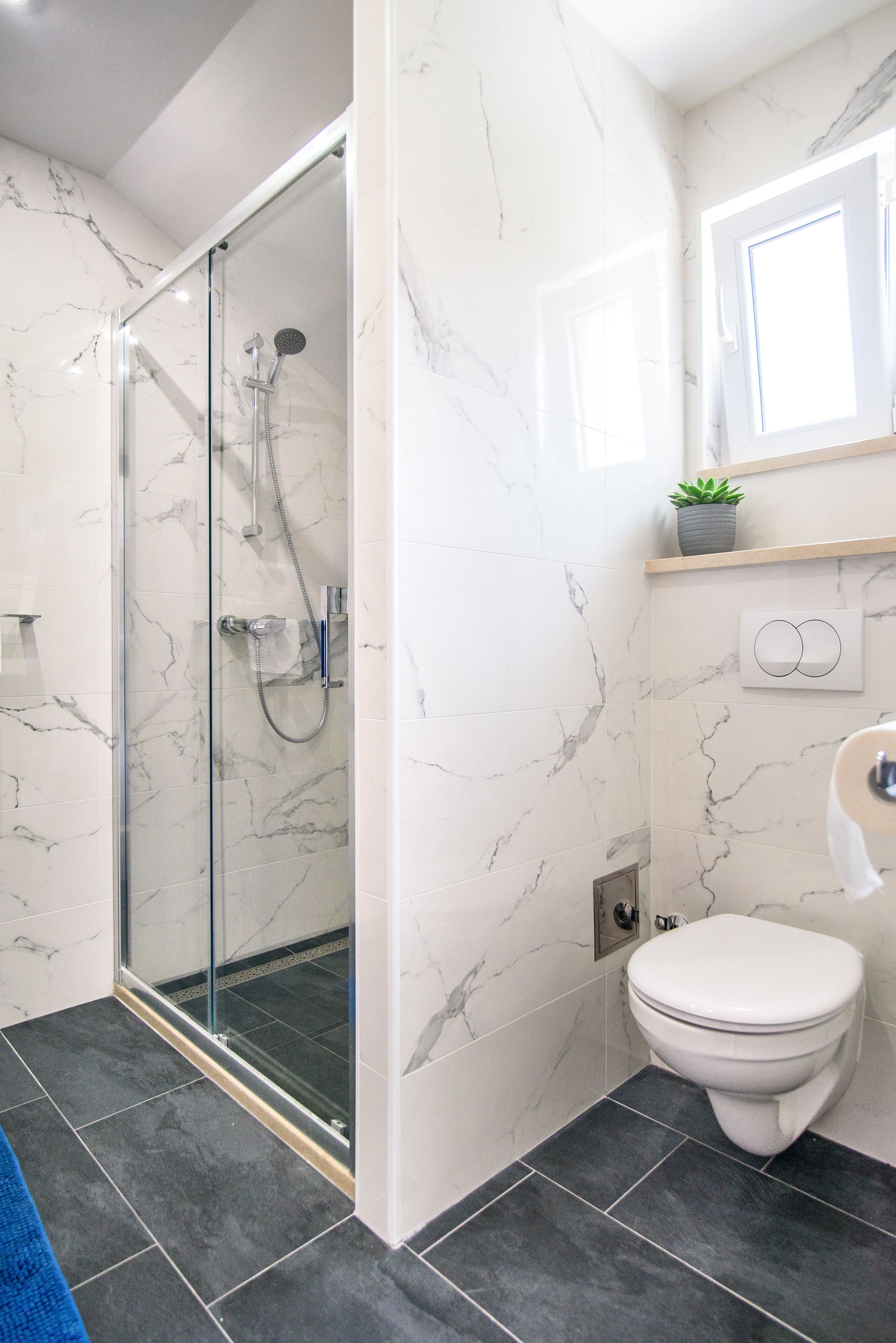 Un baño moderno con ducha de vidrio, inodoro y paredes de mármol.