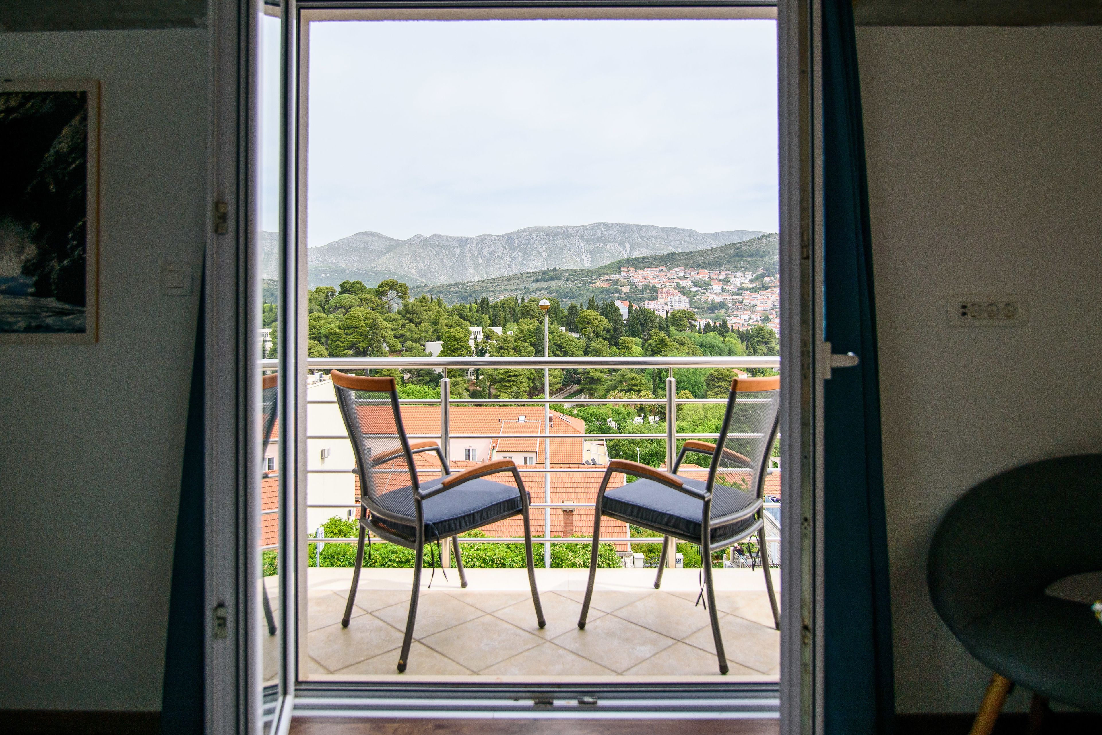 A balcony with two chairs and a view of a town and mountains.