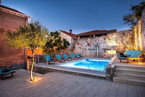 Una piscina con sillas de descanso y un muro de piedra.