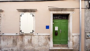 A building facade with a green door, a white door, and a window with shutters. - Sunrise Sea view (Rovinj)