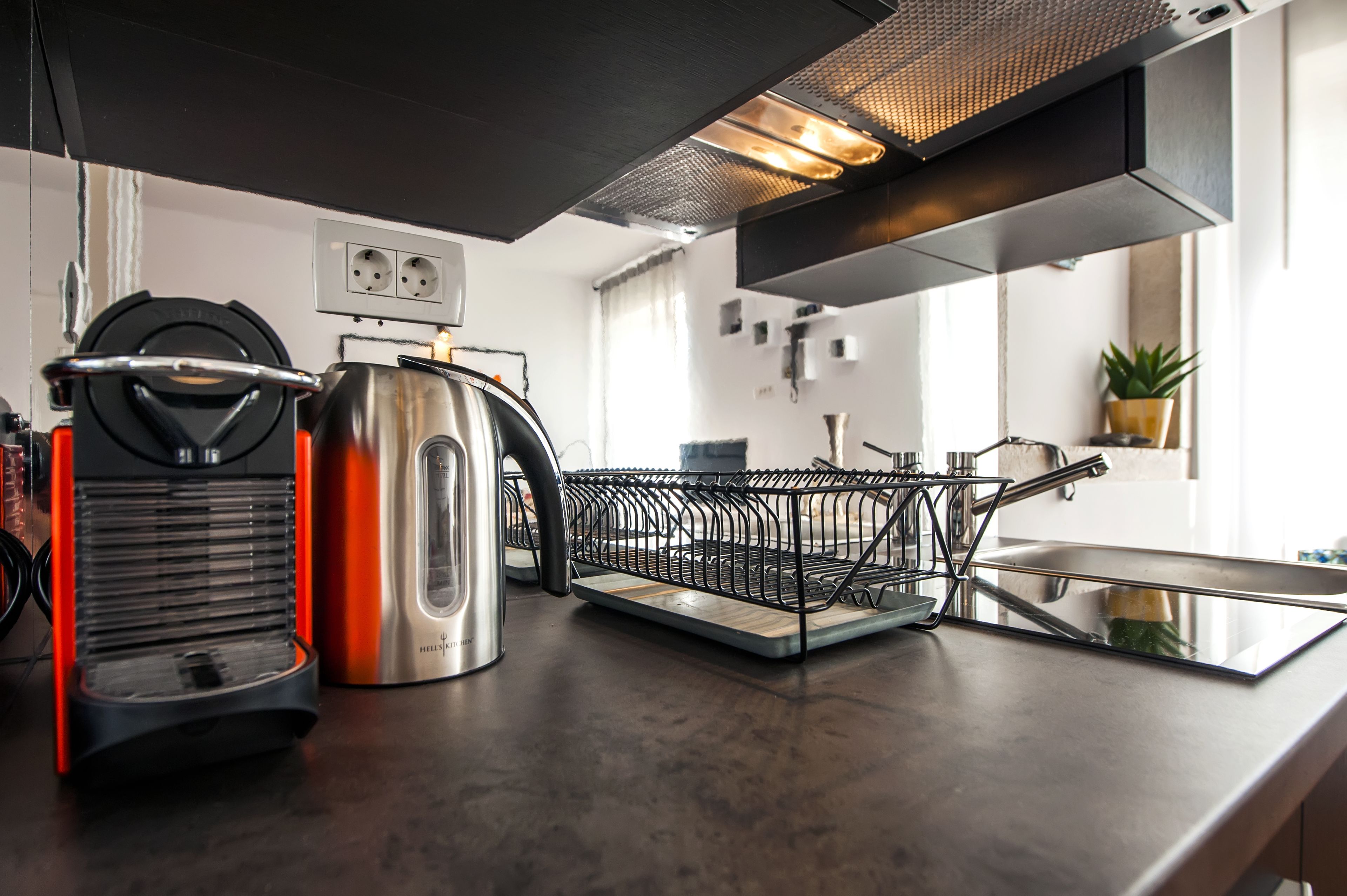 A modern kitchen with stainless steel appliances, a kettle, and a coffee maker.