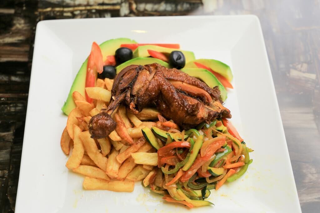 A plate of food with a roasted chicken, fries, and a vegetable salad.