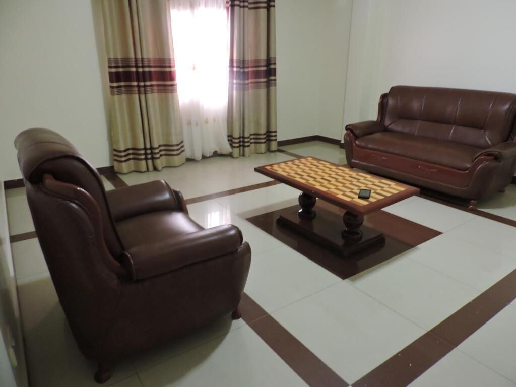 A living room with a brown leather sofa, a wooden coffee table, and a patterned rug.