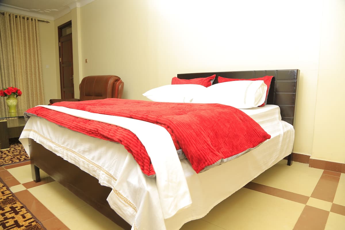 A neatly made bed with a red and white bedspread, a brown headboard, and a pair of red pillows.