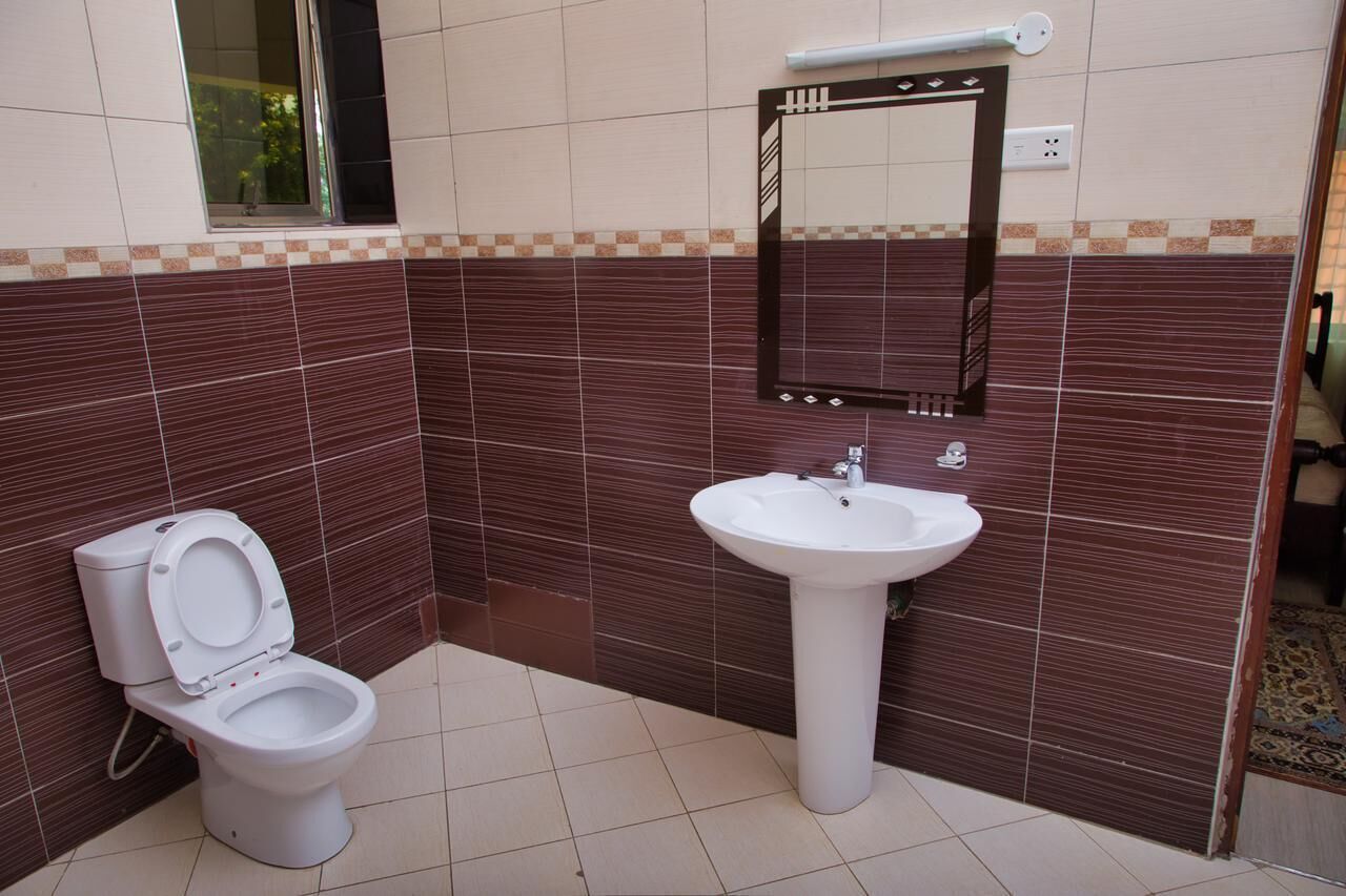 A bathroom with a toilet, sink, and mirror.