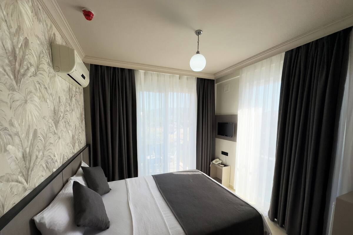 A hotel room with a bed, a TV, and a telephone.
