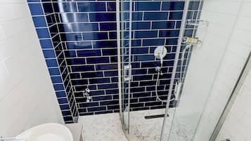 Un baño con cabina de ducha de vidrio, un lavamanos blanco y un inodoro.