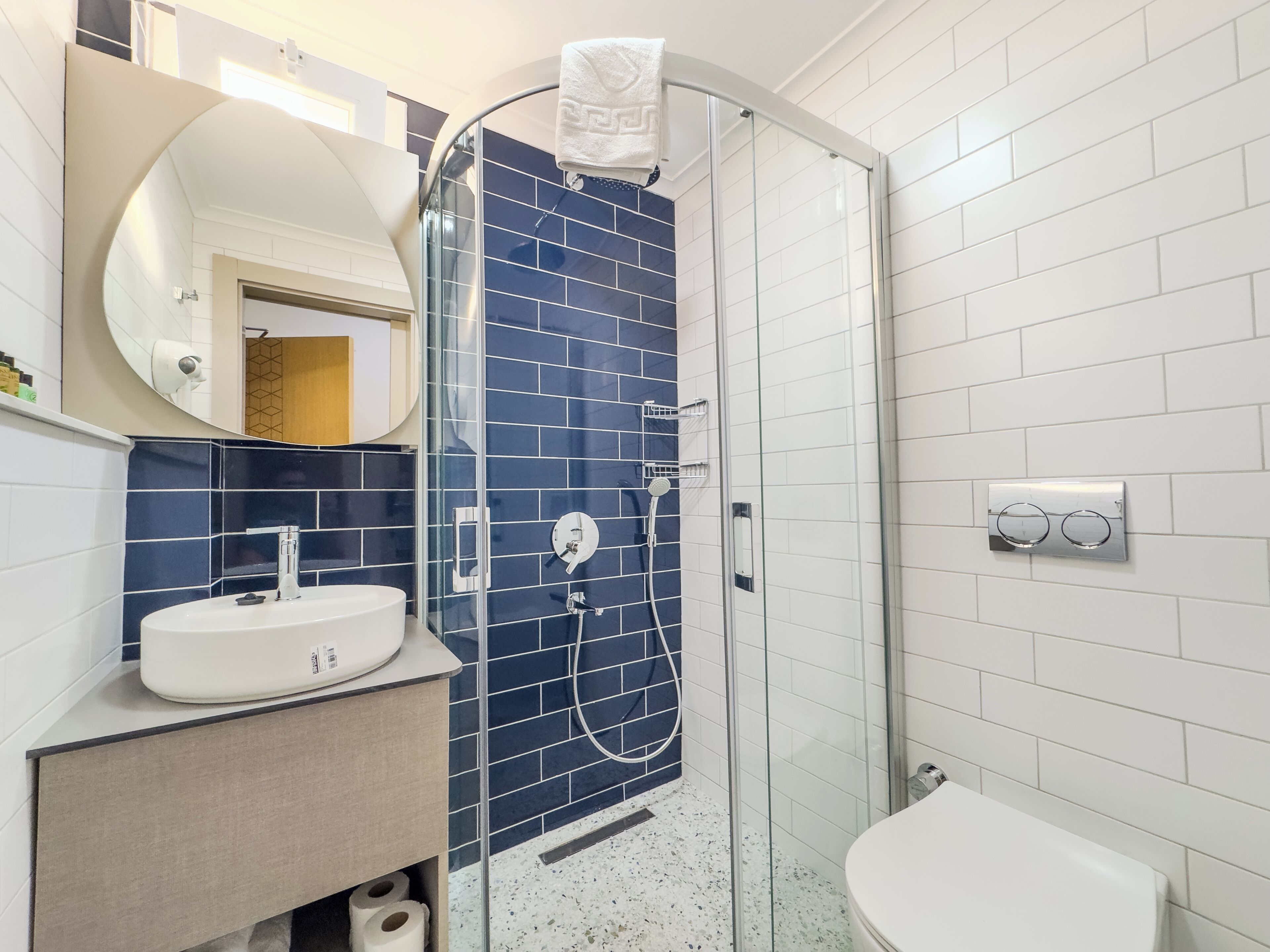 Un baño moderno con cabina de ducha de vidrio, un lavamanos blanco y un inodoro.