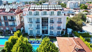 Ein Hotel mit mehreren Balkonen, einem Schwimmbad und Solaranlagen auf dem Dach.