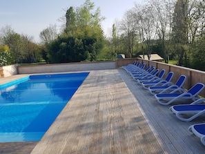 A swimming pool with a wooden deck and lounge chairs. - Camping Le Petit Lion - Lodges Bois (Vendoire)