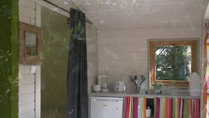 A small kitchen with a refrigerator, a coffee maker, and a window. - Camping Le Petit Lion - Lodges Bois (Vendoire)
