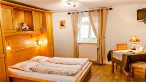 A wooden bed with two pillows and a bedside table with a lamp. - Domaine Sylvie Fahrer & Fils (Saint-Hippolyte)
