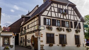 A traditional half-timbered building with multiple windows, a wooden door, and flower boxes on the facade. - Domaine Sylvie Fahrer & Fils (Saint-Hippolyte)