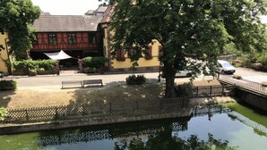 A courtyard with a pond, benches, and a building with a sloped roof. - Domaine Sylvie Fahrer & Fils (Saint-Hippolyte)