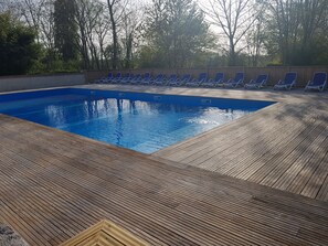 En säsongsöppen utomhuspool, parasoller och solstolar