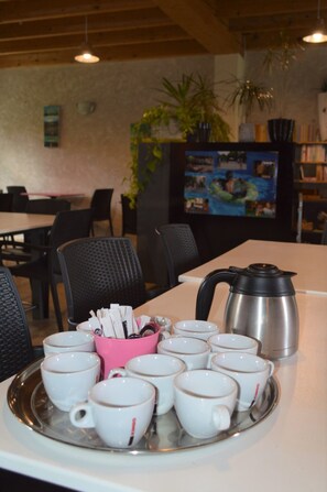 A dining area with a table set with white cups and saucers, a pink cup holder, and a silver coffee pot. - Camping Le Petit Lion - Tente Safari (Vendoire)