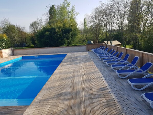 A swimming pool with a wooden deck and lounge chairs. - Camping Le Petit Lion - Tente Safari (Vendoire)