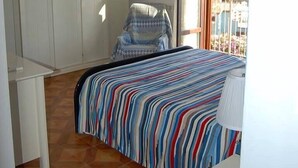 Une chambre à coucher avec un lit, une chaise, une armoire et un balcon offrant une vue.