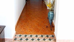 Un couloir doté d’un sol carrelé, d’une arche décorative et d’un vase contenant des fleurs séchées.