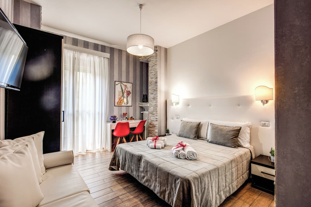 A modern hotel room with a large bed, a desk, and a chair.