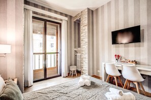 A hotel room with a bed, a desk with two chairs, a TV, a radiator, and a window with curtains. - Santamaggiore Inn (Rome)