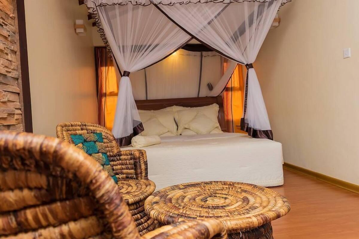 A room with a bed, wicker furniture, and a canopy bed.