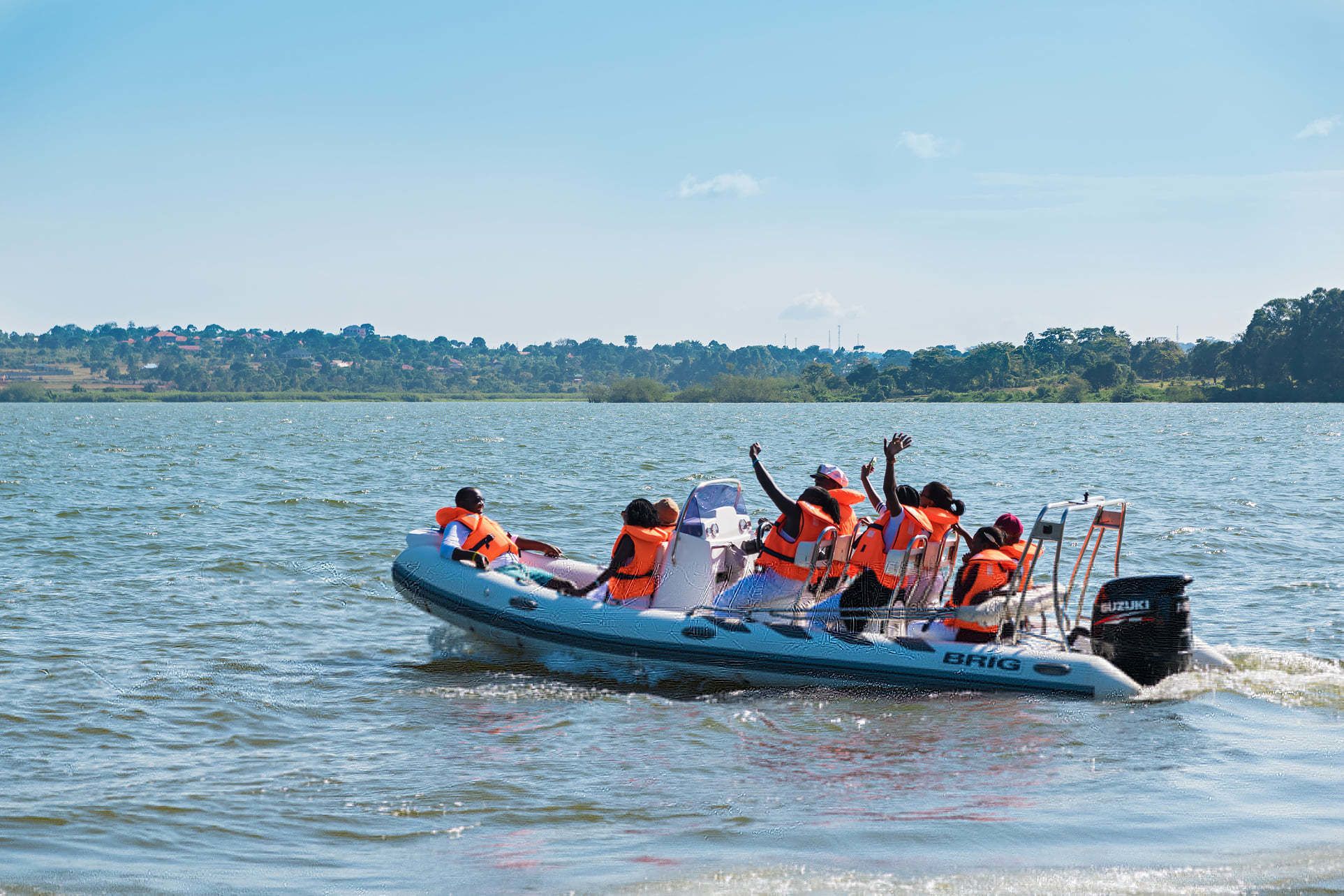 A group of people on a blue inflatable boat with orange life vests, enjoying a sunny day on the water.