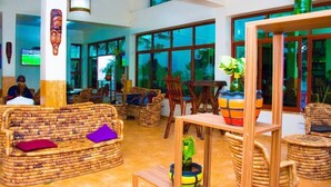 A spacious lobby with wicker furniture, large windows, and a television screen. - Nyange Resort and Marina (Entebbe)