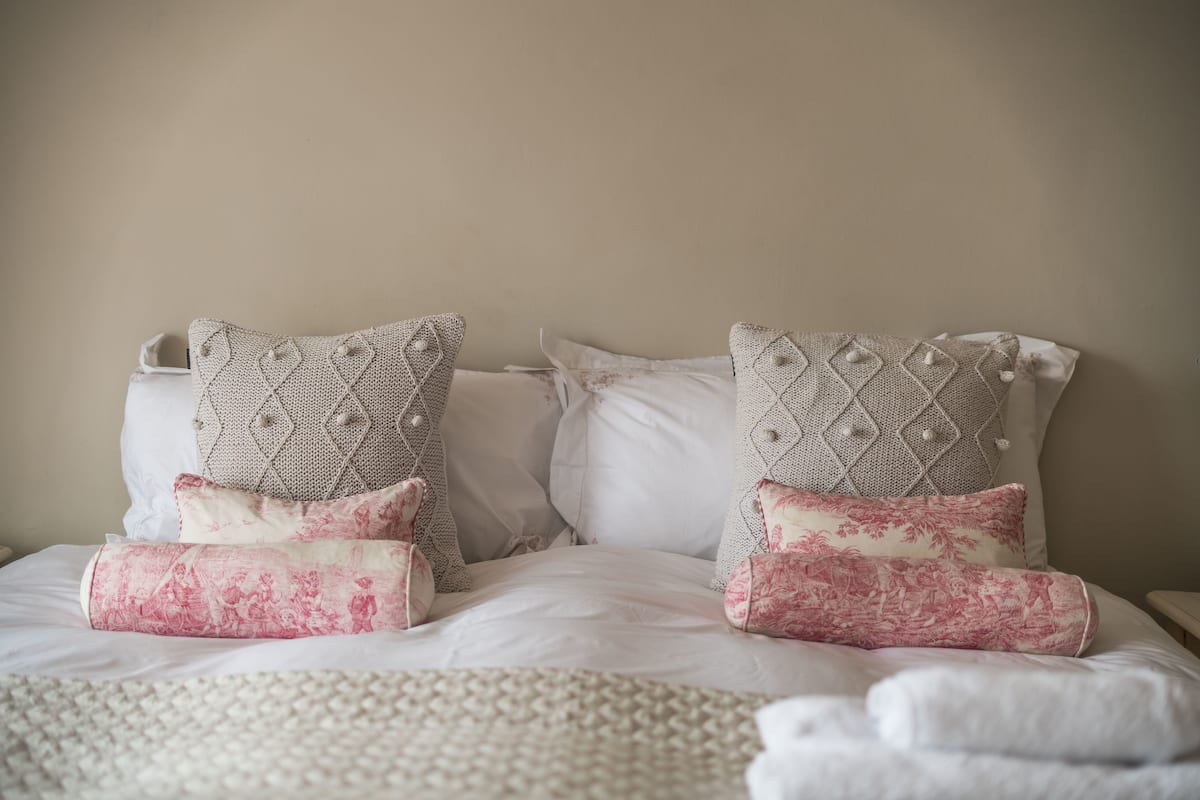 Un lit bien fait, agrémenté d’oreillers à motifs et d’une couverture à texture intéressante.