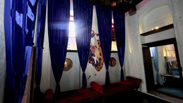 Een kamer met blauwe gordijnen, een rode bank en een muur met een decoratief symbool.