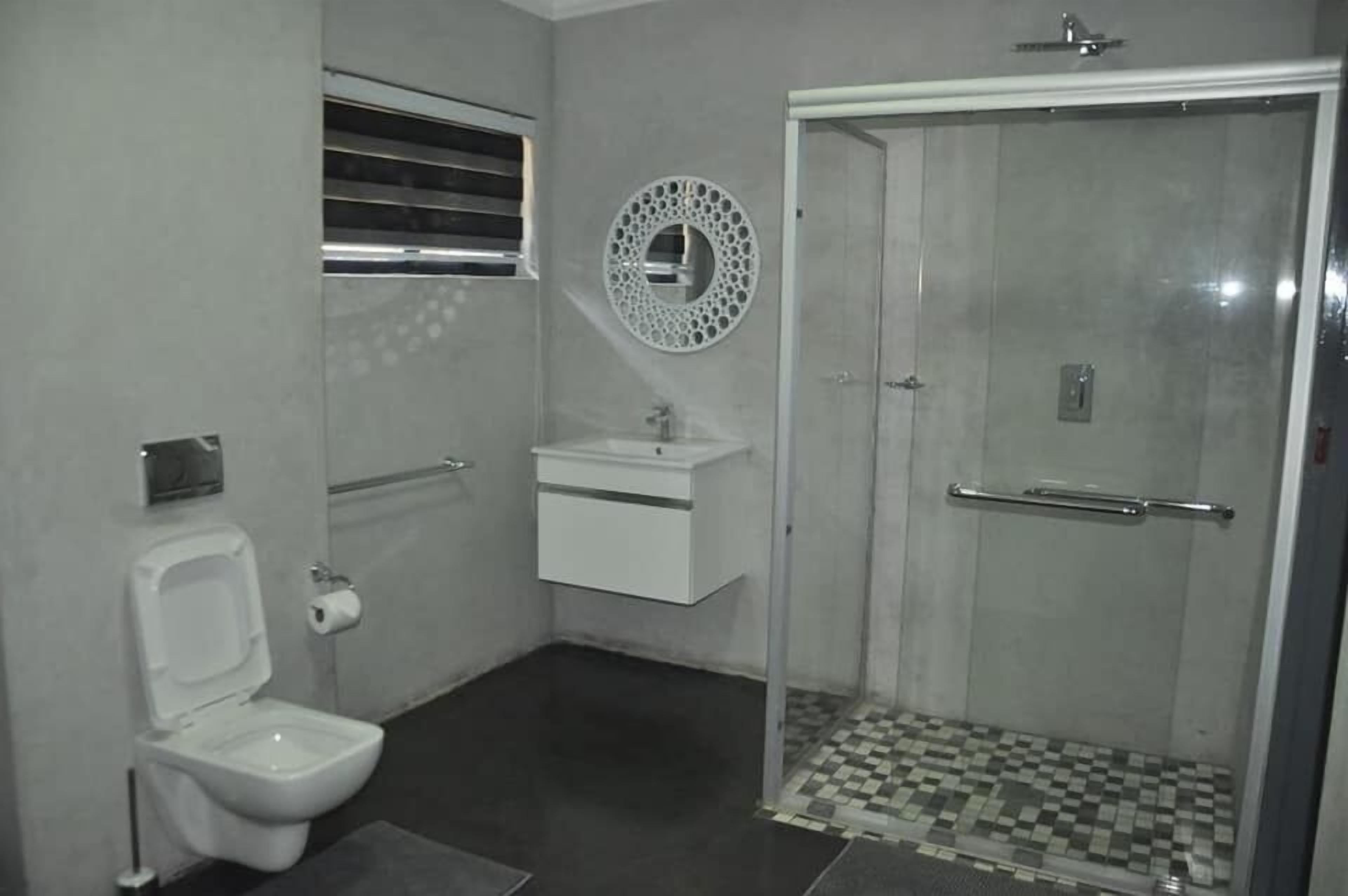 A bathroom with a toilet, sink, and shower.