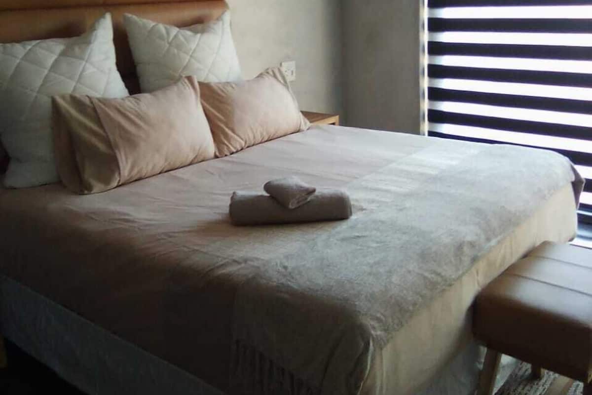 Un lit bien fait, avec une tête de lit, des oreillers et une serviette pliée.